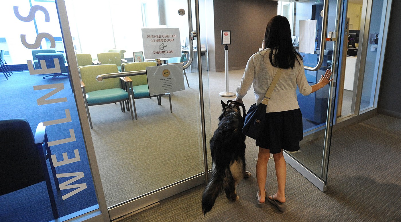 A student walking with her service dog into the Wellness Center.