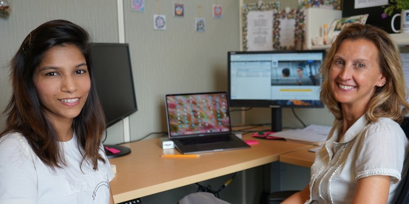 Shruti Jain sits at a desk with her supervisor at University Relations, Sarah Eisenklam